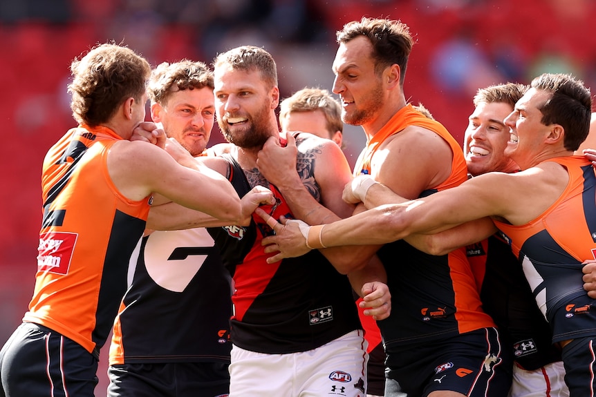 Jake Stringer grits his teeth while a number of GWS players surround him and grab at him