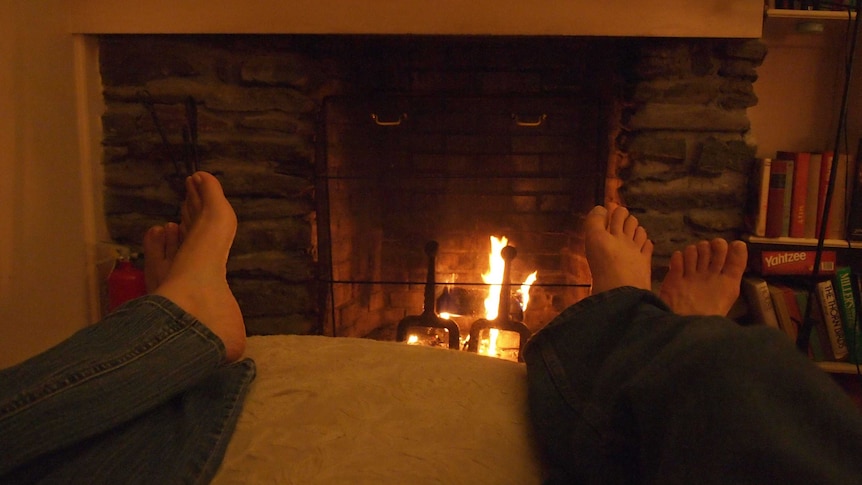 Feet on a footrest in front of an open fire.