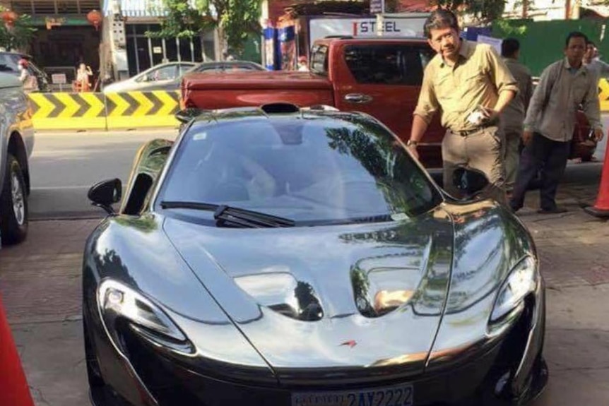 Prime Minister Hun Sen's nephew Hun To stands next to a shiny sports car