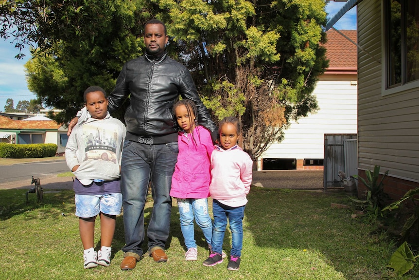 Remy Asaba stands with his children.