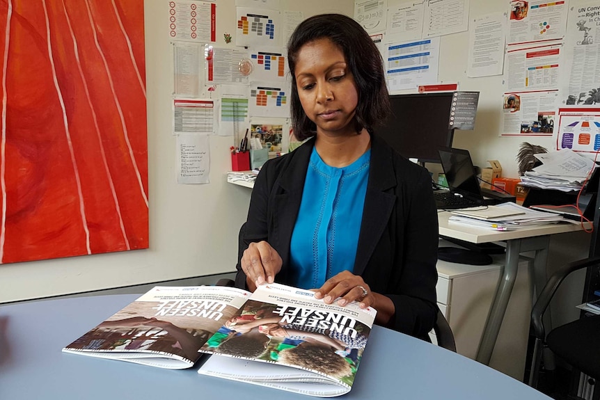 A woman in an office reading a report called Unseen, Unsafe