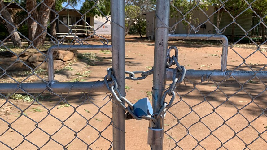 a padlock on a gate with a TAFE building in the distance