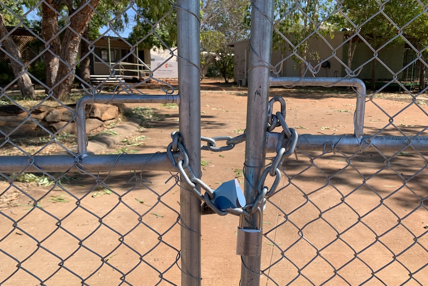 a padlock on a gate with a TAFE building in the distance