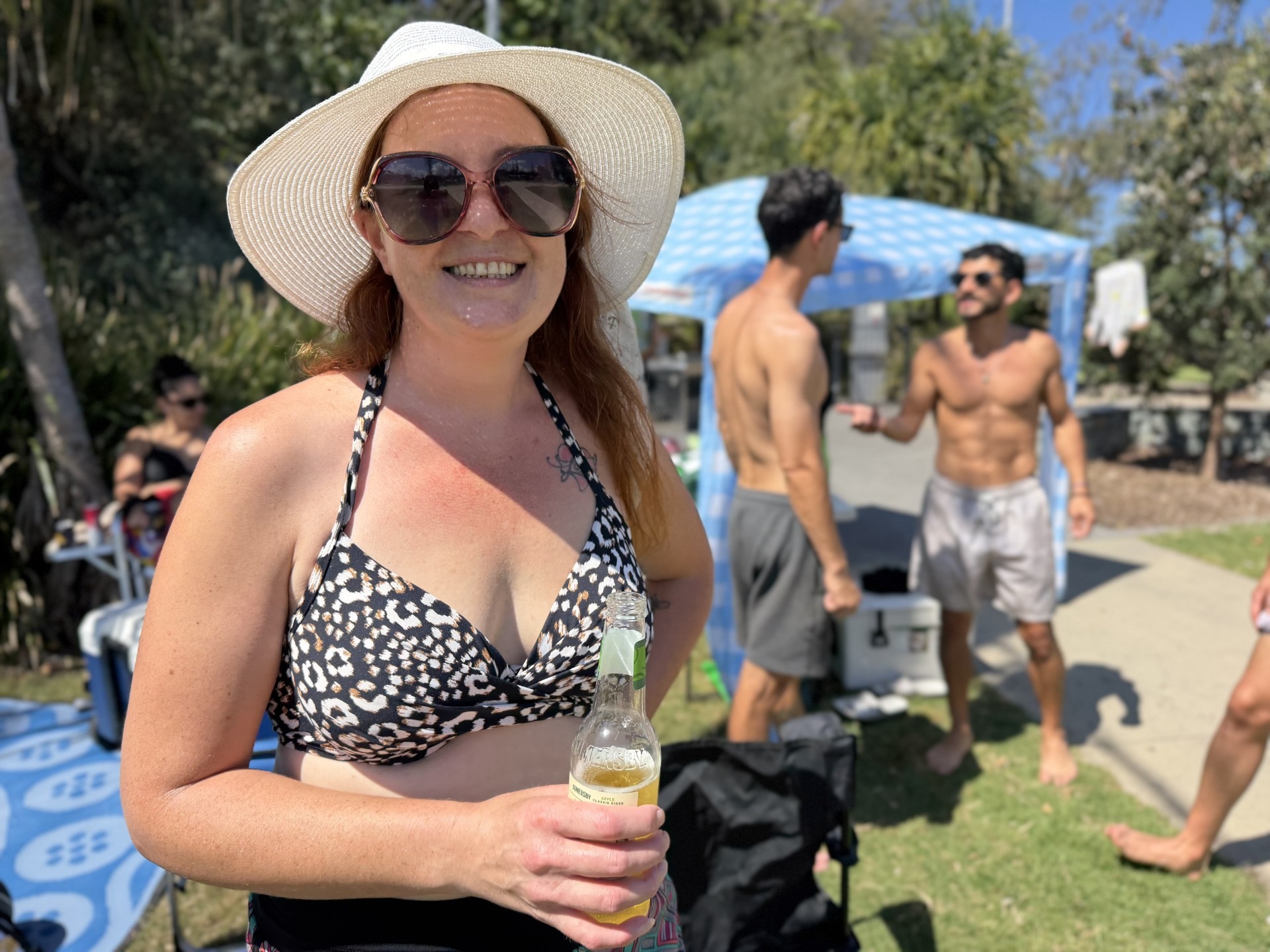 A young woman smiling, holding a beer