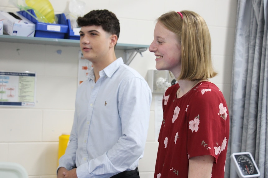 A man and a woman look at something off camera, smiling