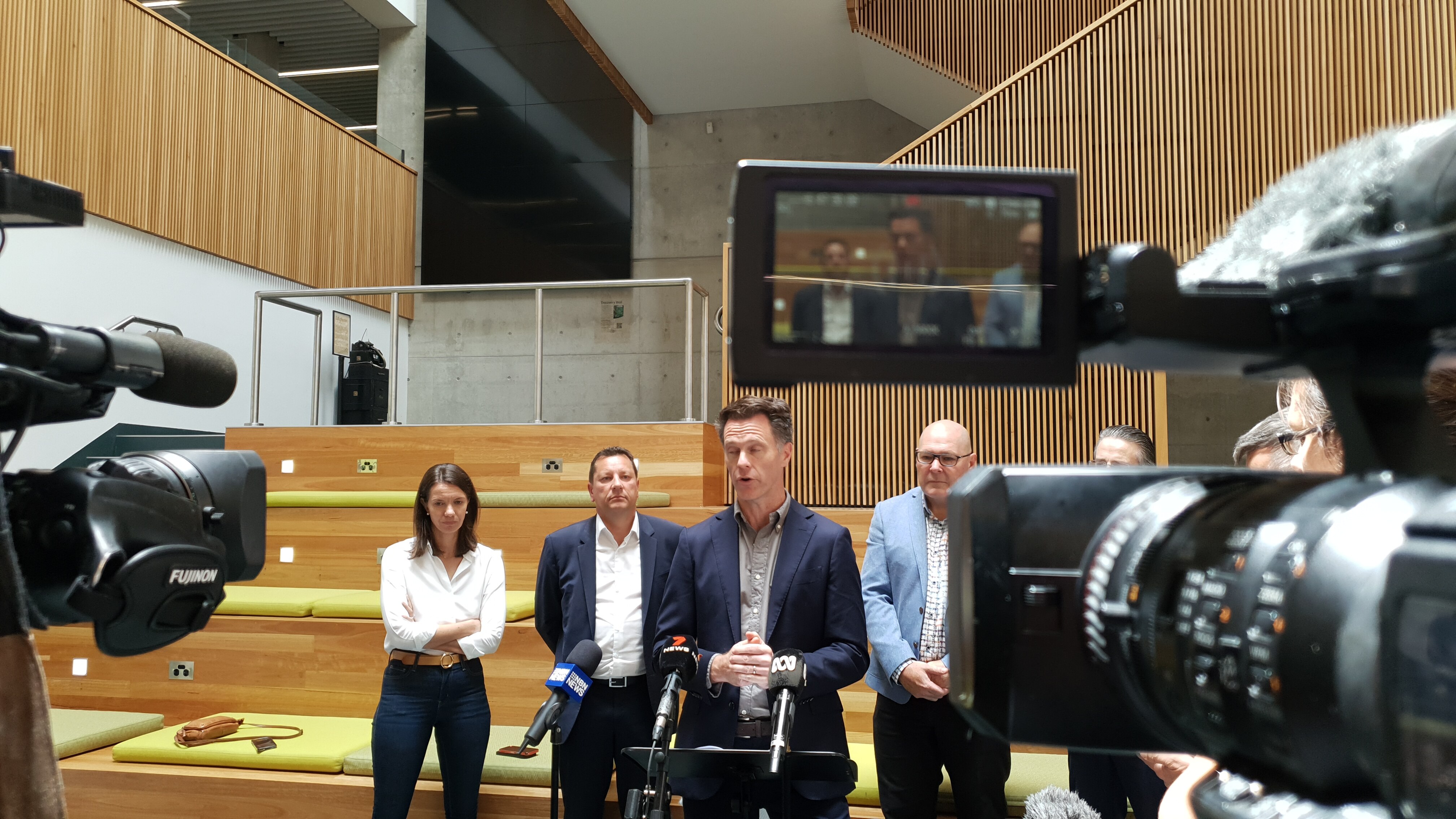 Cameras focus on a man in a blue suit, flanked by others in similar attire
