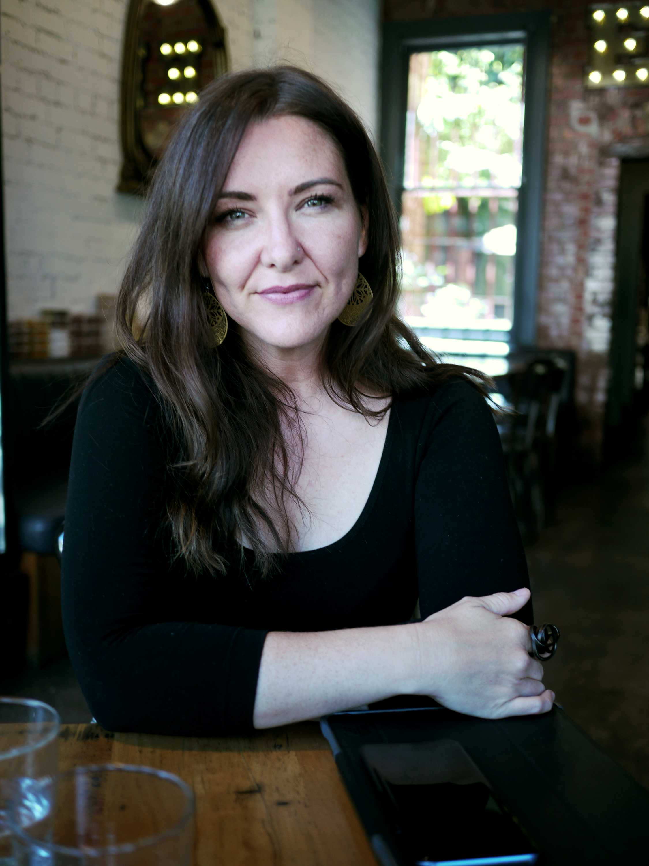 Woman with long brown hair looking at camera and smiling