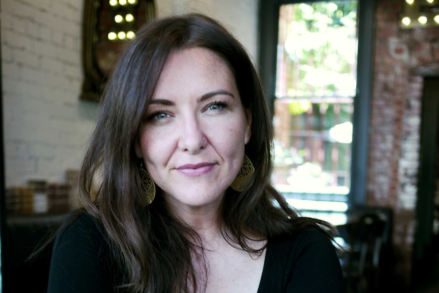 Woman with long brown hair looking at camera and smiling