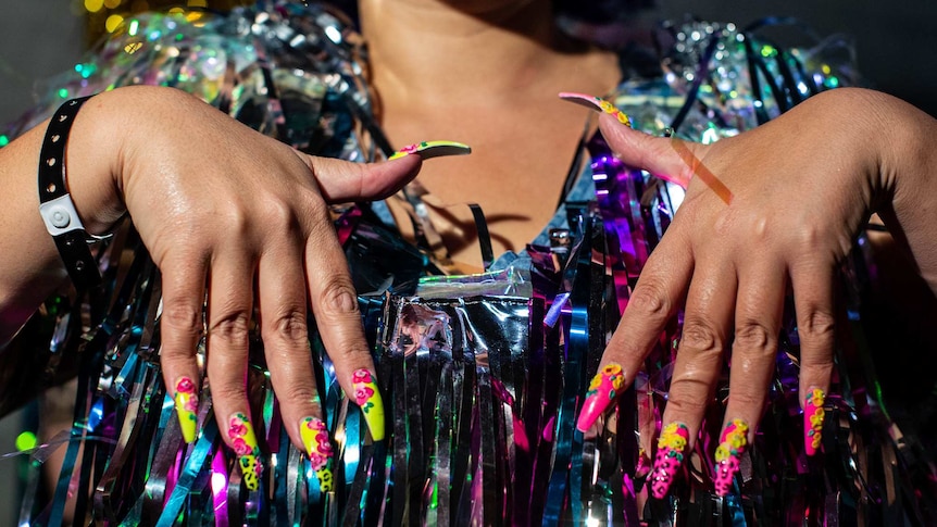 Closeup of woman's hands, showing colourful painted nails.