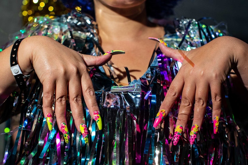 Closeup of woman's hands, showing colourful painted nails.