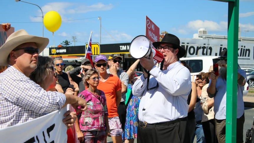 George Christensen holds a megaphone, surrounded by people.