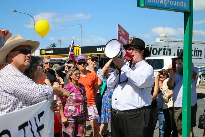 George Christensen holds a megaphone, surrounded by people.
