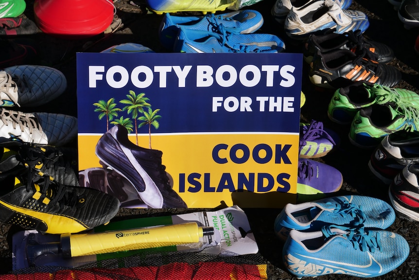 Picture of sign "Footy Boots for the Cook Islands" with boots all around it.