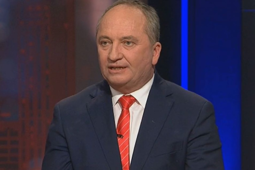 Barnaby Joyce wears a dark suit with red and white striped tie.