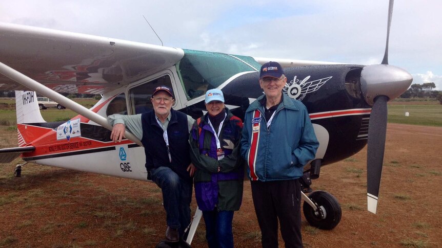 Jan, Penny and Murray stand between the propeller and wing of the small four seater Cessna aircraft on an overcast day.