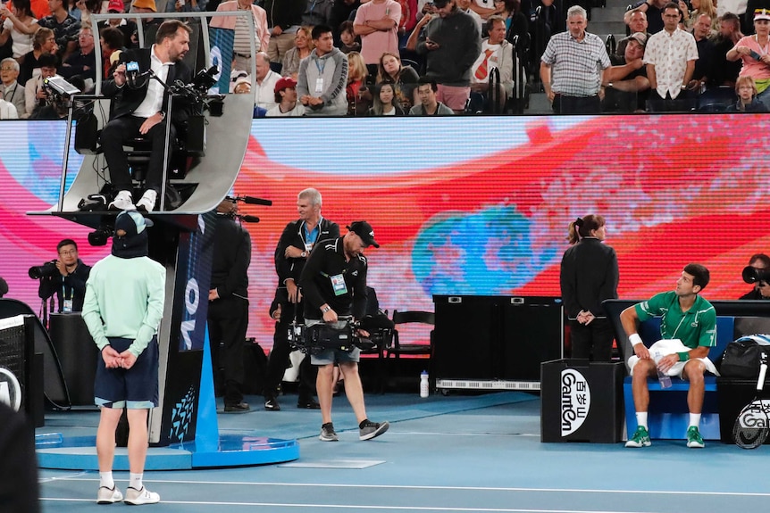 A tennis player stares up at the umpire during the change of ends.