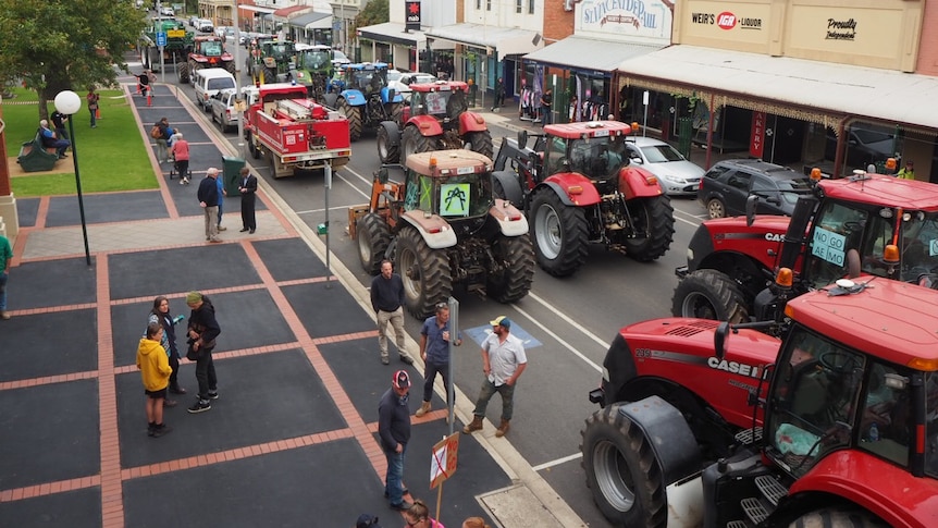 Tractors and trucks drive down a main street during a protest.