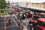 Tractors and trucks drive down a main street during a protest.