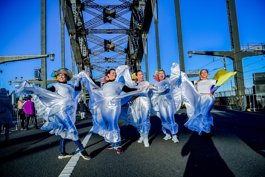 A group of women in white costumes walk on the Sydney Harbour Bridge supporting the Colombian Women's World Cup team.