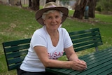 Susan Gascoine seated at a park bench.