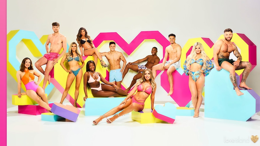 Eleven Love Island contestants posing in swimsuits against a set, in story about dating preferences like blonde and blue eyes.