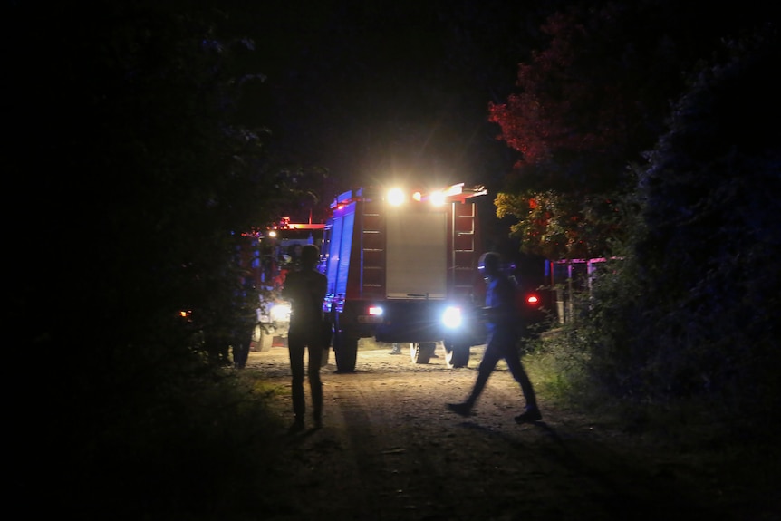 Firefighting vehicles are seen in the dark near the site of a plane crash.