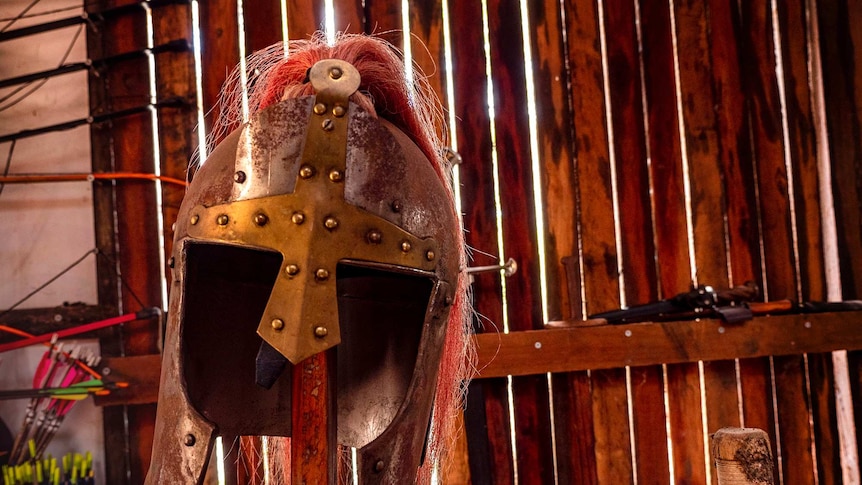 A metal medieval war helmet on a stand.