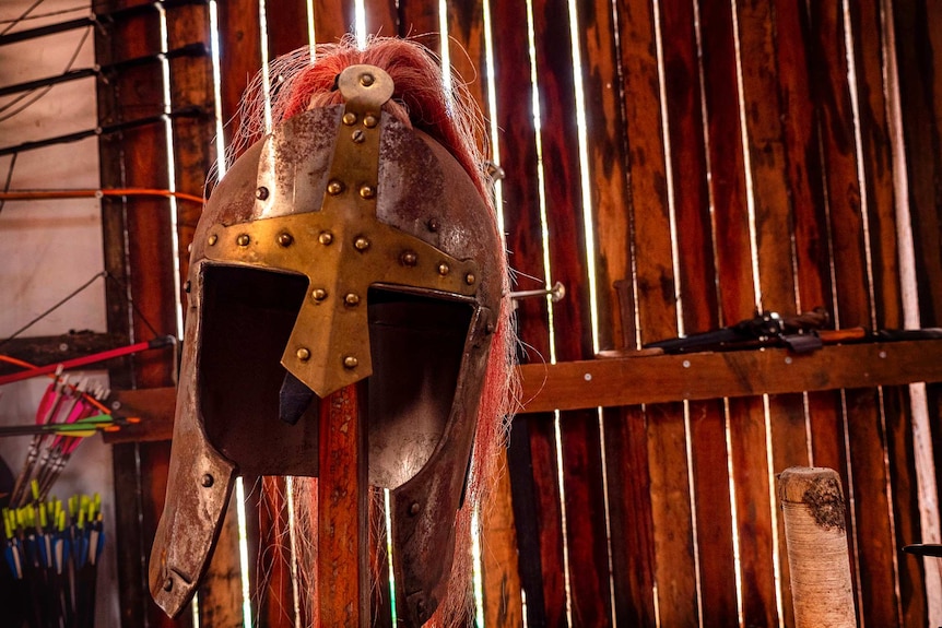 A metal medieval war helmet on a stand.