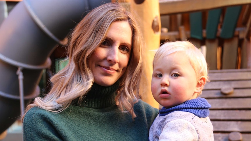 Karli smiles while baby Quinn looks confused, staring into the camera.