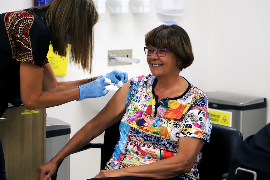 A woman with glasses and short hair gets a COVID-19 vaccination.