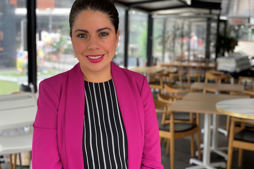 A smiling, dark-haired woman in a bright-coloured blazer.