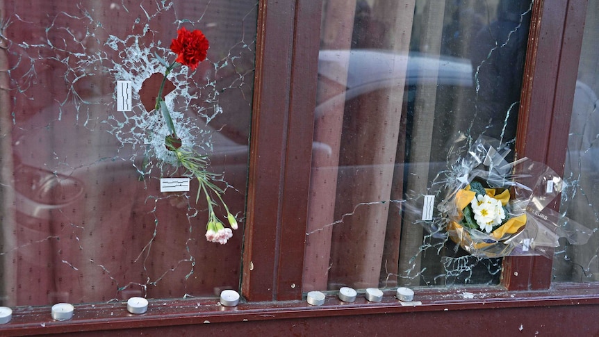 Flowers placed in bullet holes at a memorial site outside of the Carillon bar for victims of the terrorist attacks in Paris.