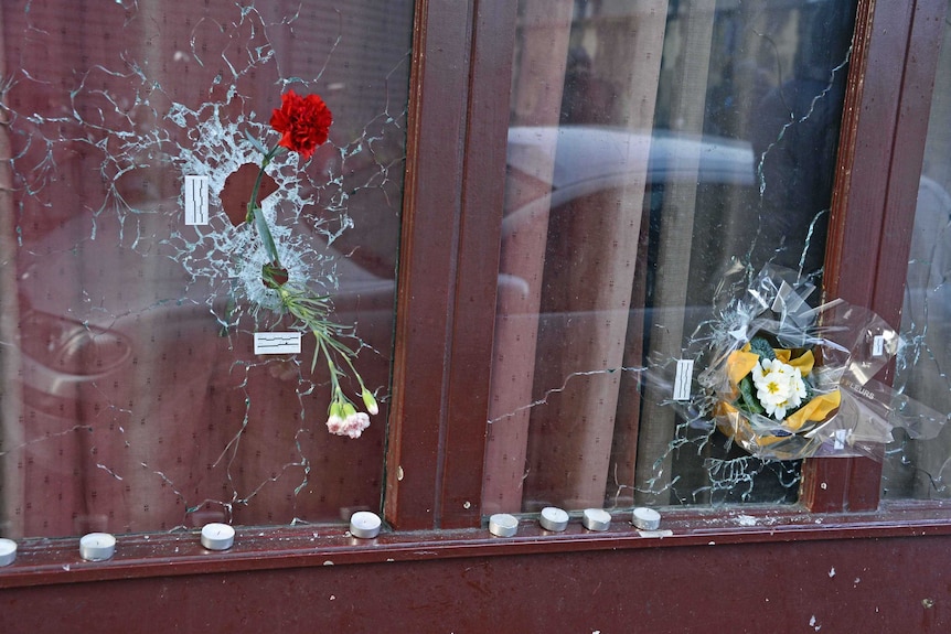 Flowers placed in bullet holes at a memorial site outside of the Carillon bar for victims of the terrorist attacks in Paris.