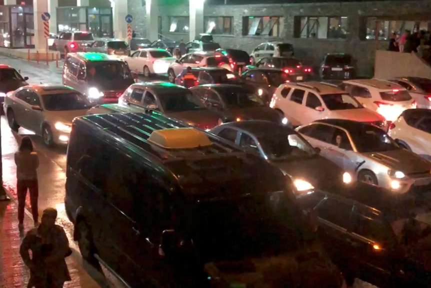 a long line of cars at a border checkpoint in the dark