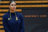 Basketballer Liz Cambage stands looking serious, next to a sign saying "Everybody's Game".