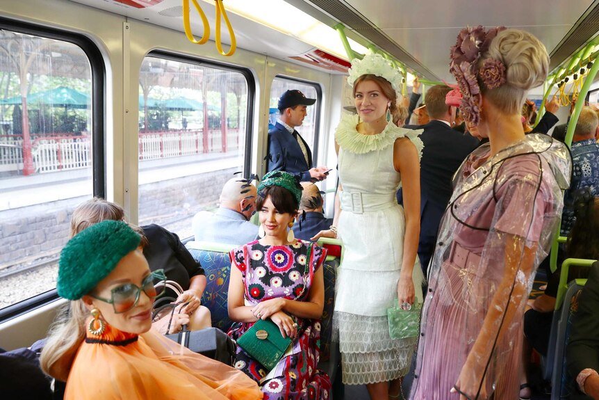 A group of four fashionably dressed women on a train at Flinders Street station.