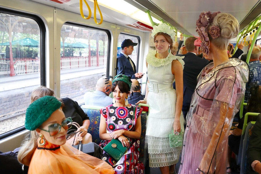 A group of four fashionably dressed women on a train at Flinders Street station.