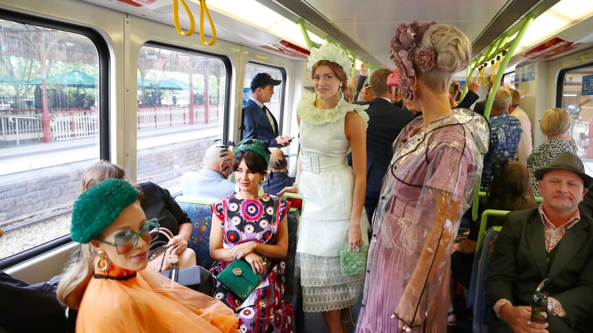 A group of four fashionably dressed women on a train at Flinders Street station.