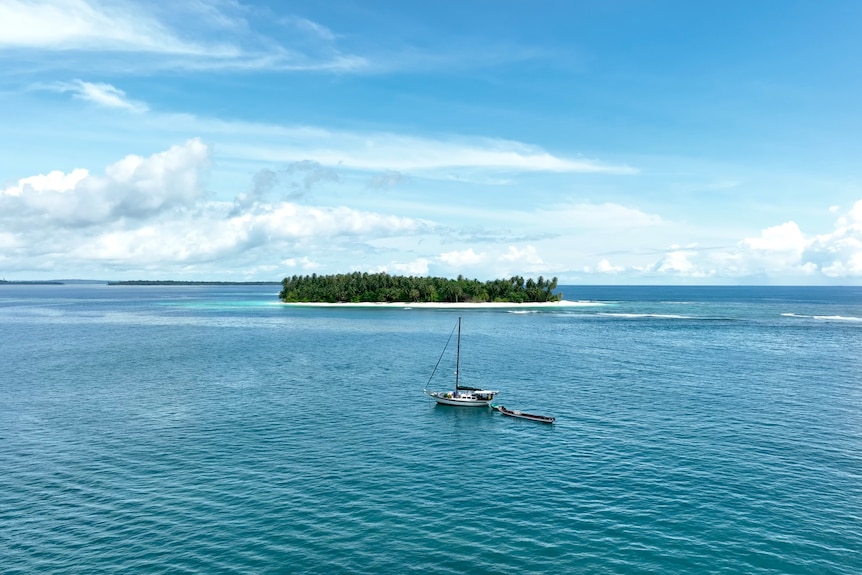 a sail boat anchored off a remote tropical island