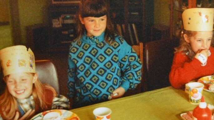 Three children sitting at a table at a birthday party.