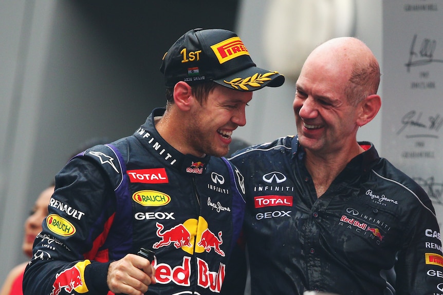 A racing driver and his technical director, stading arm in arm on a podium, drenched in champange, smiling