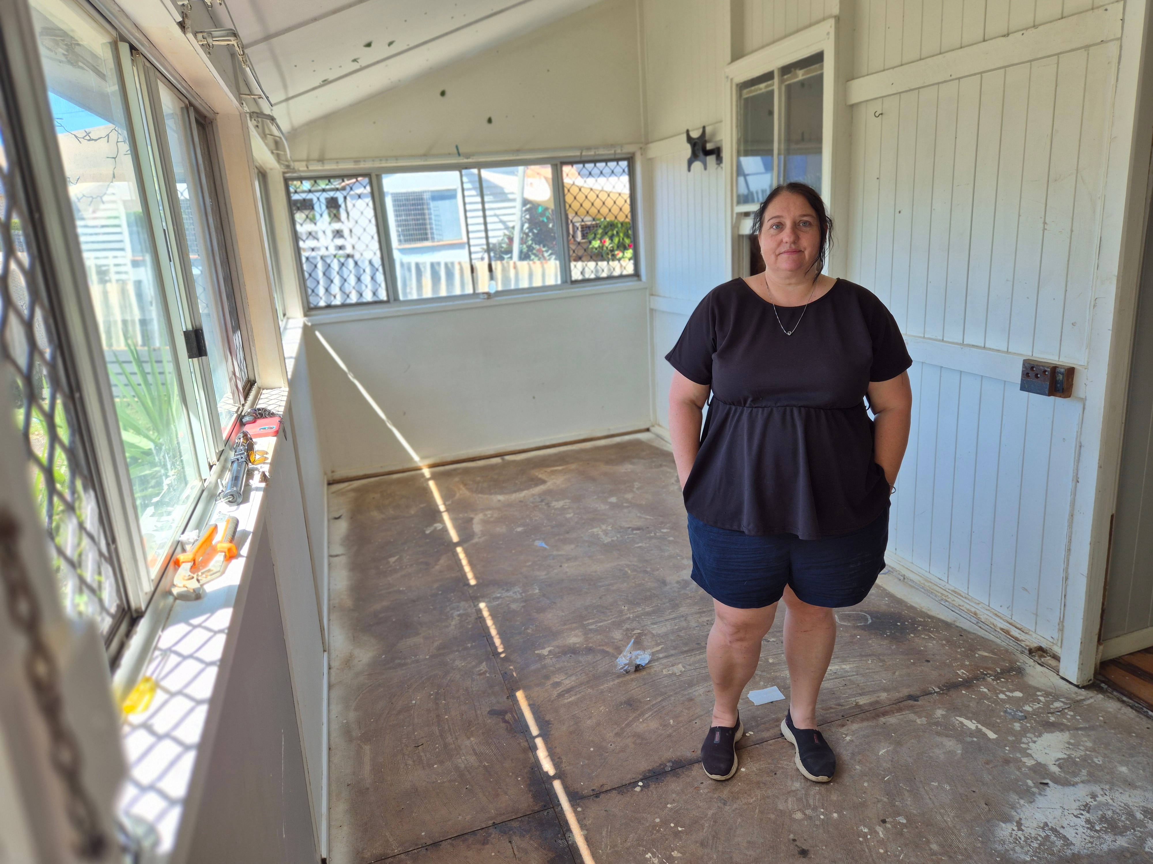 A woman stands in an empty but muddy room.