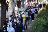 People queue while wearing masks