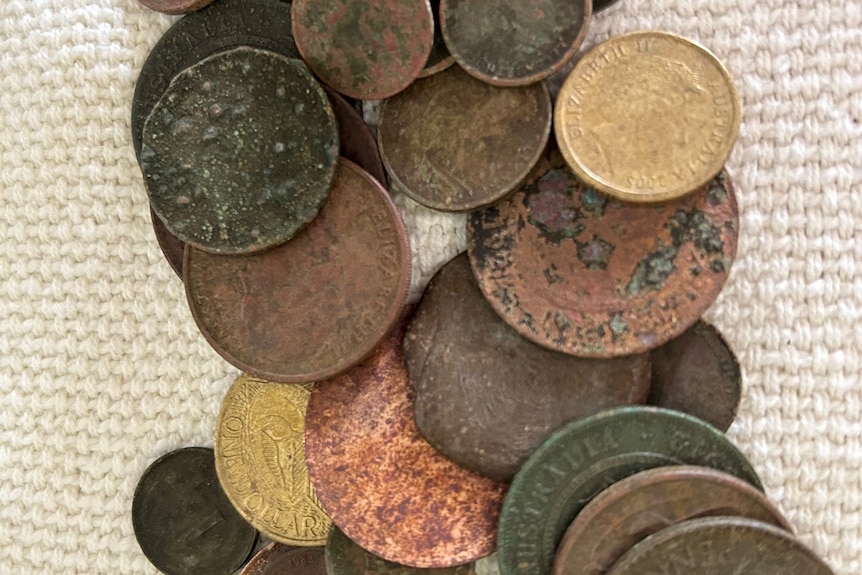 A small pile of rusted old coins is seen on a table.