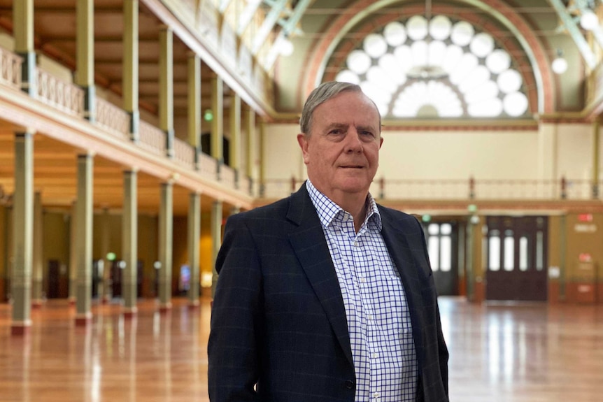 Peter Costello wears a dark jacket and a check shirt