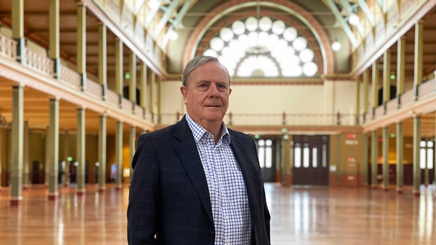 Peter Costello wears a dark jacket and a check shirt