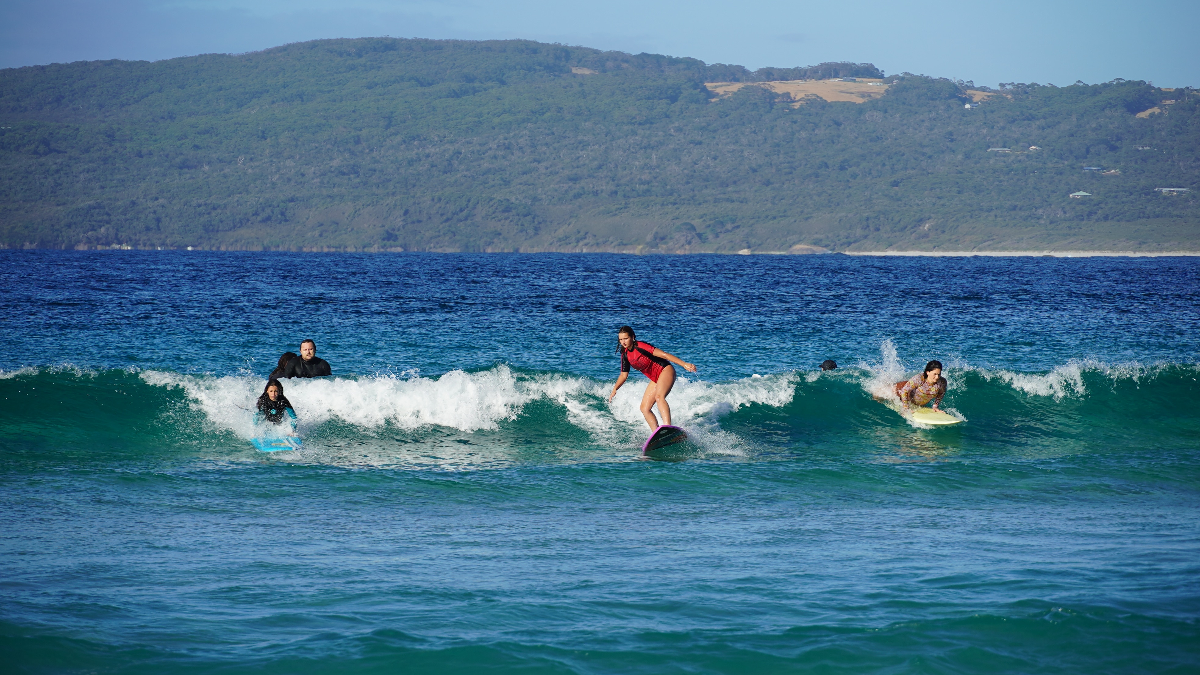 Tres personas surfean una ola. 