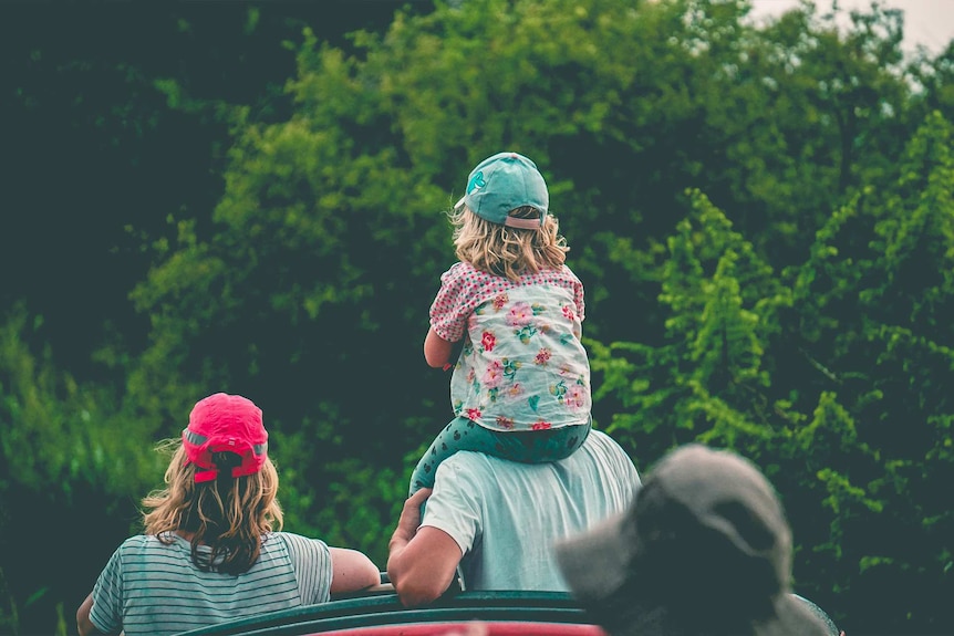 A family of four, with young girl on Dad's shoulders, in the bush for a story about what travel insurance doesn't cover.