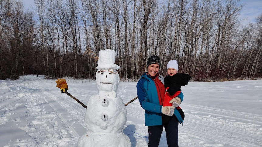 Kate Jeffries and her son in front of a snowman in Canada.