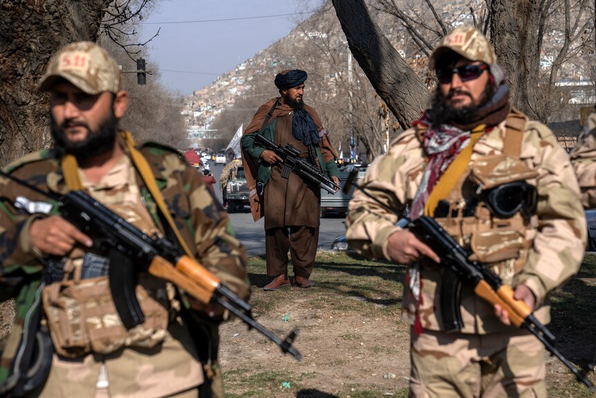 Three Taliban men hold guns as they walk the streets of Kabul.